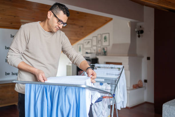 istock Man Hanging Laundry On Drying Rack In Room 1992088457