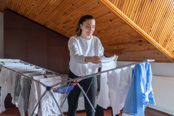 istock Woman Hanging Laundry On Drying Rack In Room 1992095307