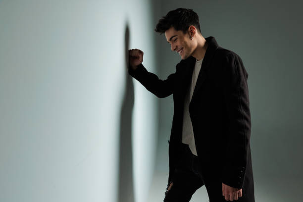 istock sexy happy man in dark coat laughing, looking down and touching wall 1992105378