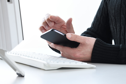 Man's hand using smart phone on working desk