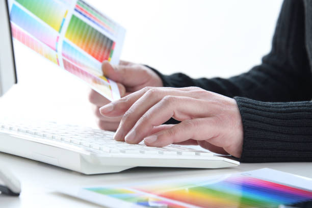 Man's hand using PC and color chart in casual clothes