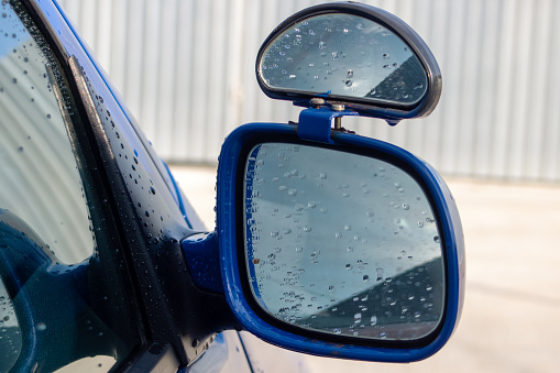Car side mirror with water droplets close up