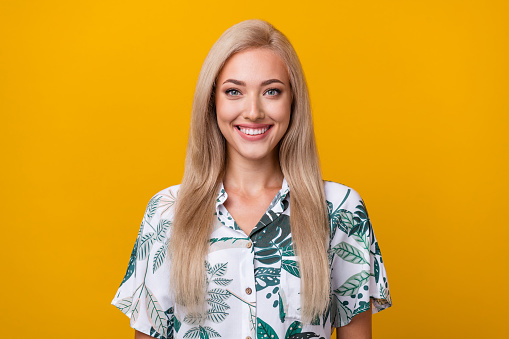 Photo of gorgeous toothy beaming lovely woman with straight hairdo dressed print shirt smiling isolated on yellow color background.