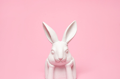Pink Easter background with white bunny, copy space . Easter greeting card