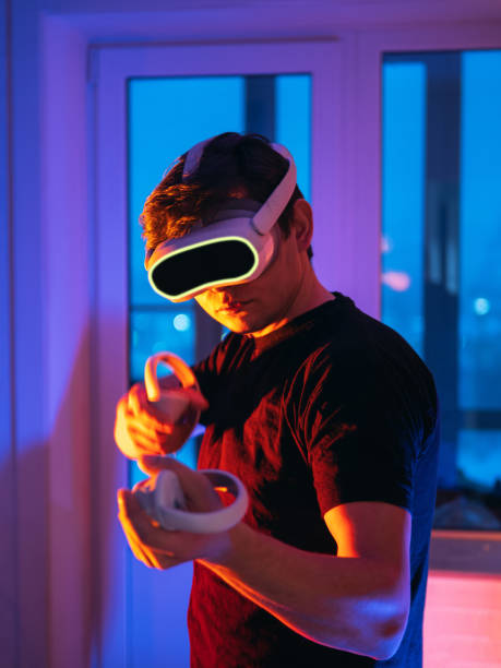 istock A young man in a virtual reality headset and gamepads with controllers, playing a shooting game. Modern technology, play VR video games. 1992189356