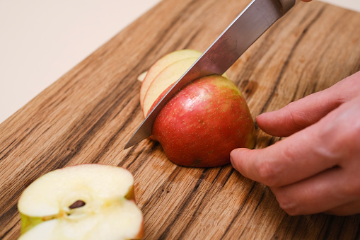 a woman in her kitchen prepares an apple dessert, close-up of hands with a knife and apples in her hands