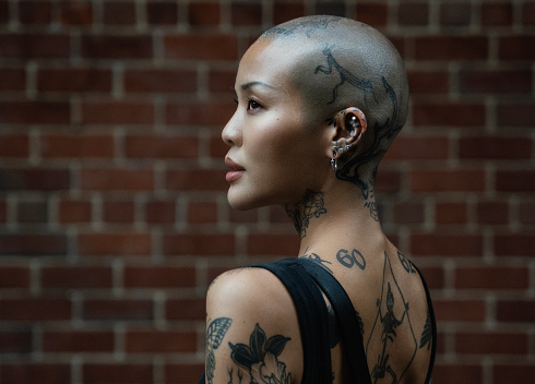 Street portrait of a young, beautiful bald woman with many tattoos