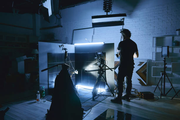 istock Video production backstage. Behind the scenes of creating video content, a professional team of cameramen with a director filming commercial ads. Video content creation, video creation industry. Low key, selective focus, film graine 1992218190