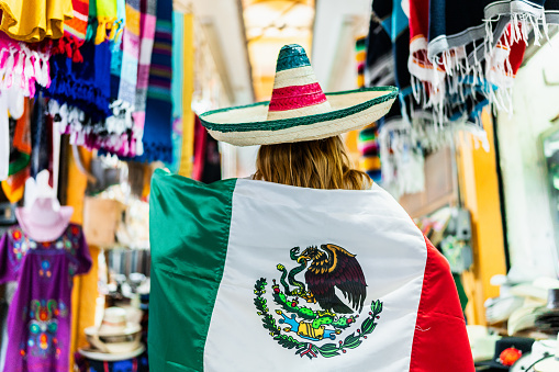 Horizontal view of a Mexican national flag waving in the wind against a clear blue sky.