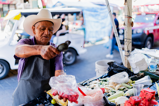 Senior man selling fruit to customer at market stall