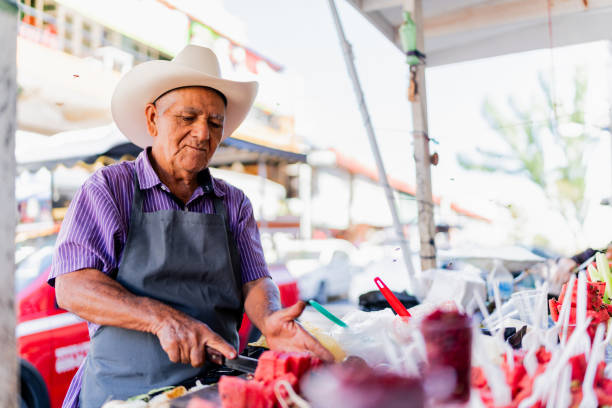 istock Senior man selling fruit to customer at market stall 1992227268