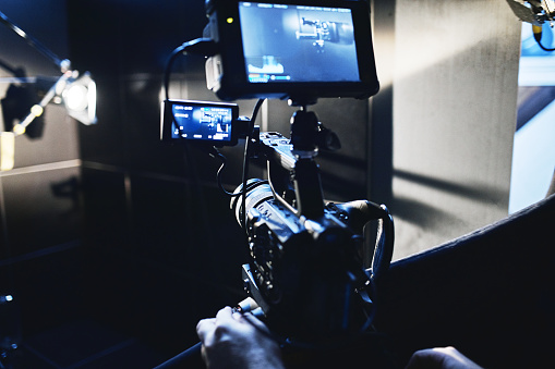 Video production backstage. Behind the scenes of creating video content, a professional team of cameramen with a director filming commercial ads. Video content creation, video creation industry, Low key, selective focus, film graine.