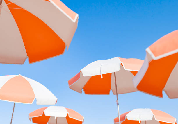 Cluster of Orange and White Beach Umbrellas Against Clear Sky