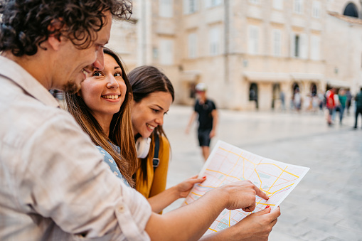 Three young tourists reading a map on the street in Dubrovnik in Croatia.