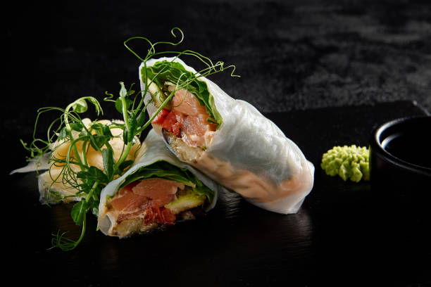 istock Salmon and avocado sprint roll with green pea sprouts on a black textured slate 1992247021