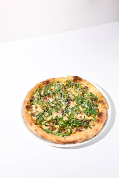 istock Italian pizza with cheese and mushrooms, topped with fresh arugula 1992247533