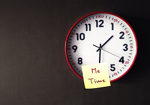 Red clock on copy space wall with stick note written ME TIME, the alone time person has to himself or herself, time spent focusing on oneself and only doing things one wants to do