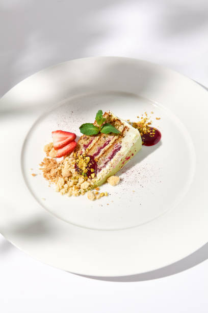 istock Pistachio cake with raspberry filling and crumbled cookie-pistachio topping, accented with shadows on a white background 1992247844