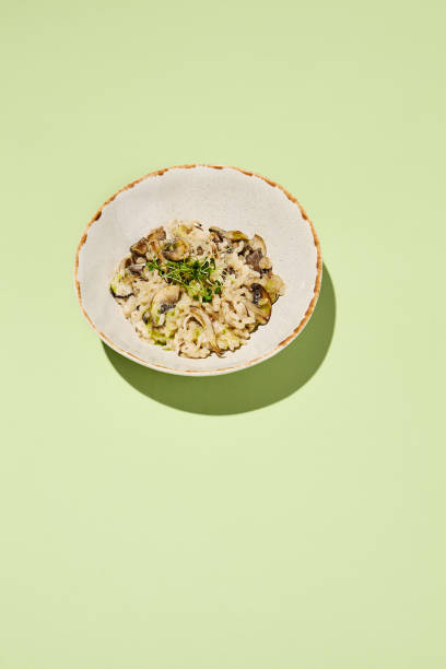 istock Mushroom risotto with truffle oil, elegantly served on artisanal tableware, highlighted by a harmonious green background for a luxury meal experience 1992248103