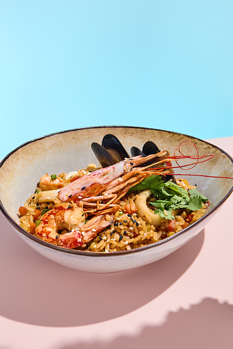 Elegant shrimp and mussel paella in a ceramic bowl with garnishes, ideal for food blogs and culinary presentations.