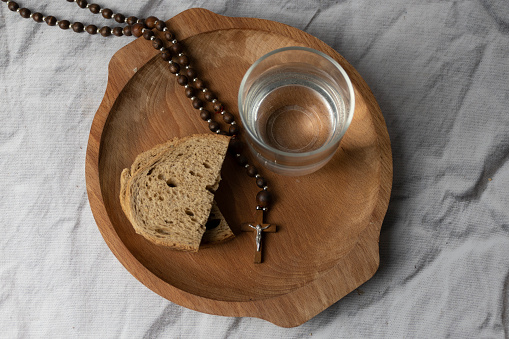 Lent - bread, water and rosary on a plate