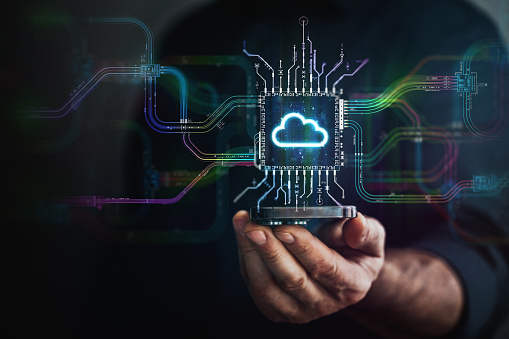 Digital cloud technology in your hand. Male hand holding futuristic cloud chip in the center and circuit board with vibrant data transfers, representing evolving technology of the future.