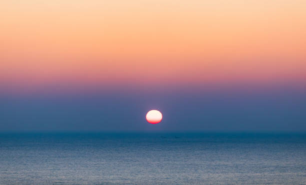 istock Sea sunrise landscape. Sunlight reflecting on the sea surface and a ship passing between it 1992291405