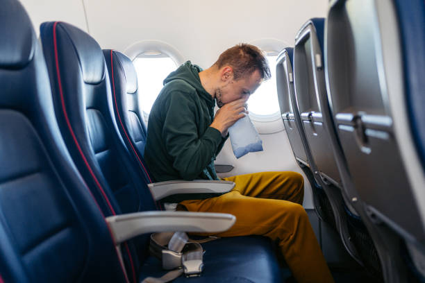 istock Young Man Vomiting In A Sick Bag In An Airplane 1992291974