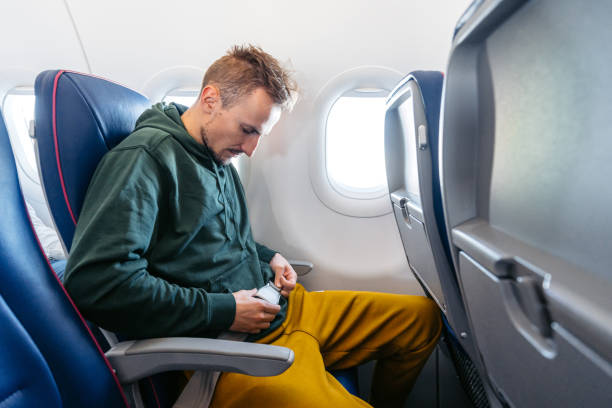 istock Young Man Fastening His Seatbelt In An Airplane 1992292535