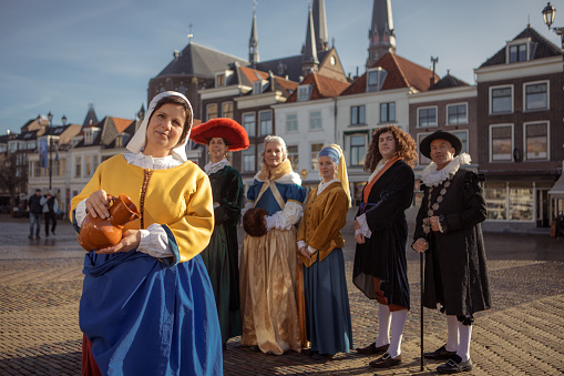 Girl with a pearl earring with a group of traditionally dressed male and female tourist guides in Delft on a spring day