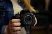 The girl holds a black camera in her hand