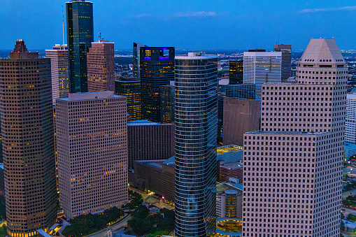Aerial view of a group of buildings located in downtown Houston, Texas shot at dusk via helicopter from an altitude of about 900 feet directly over the city.