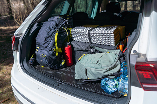 Touristic, camping equipment in the open trunk of SUV in the woods