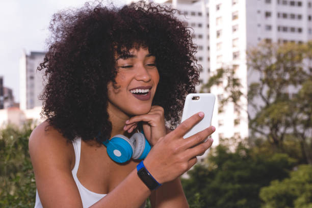 Woman laughing and looking at cell phone screen. Urban background