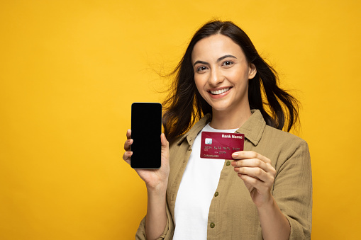 Portrait of woman credit card eshopping advertisement advertise mobile phone e-commerce isolated yellow background
