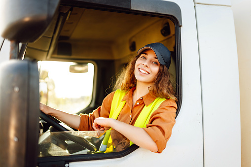 Female driver looking out of truck window. Transport industry theme