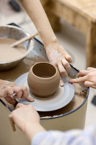 istock teacher helps the student to remove the finished work from the potter's wheel with the help of string cutter 1992454676