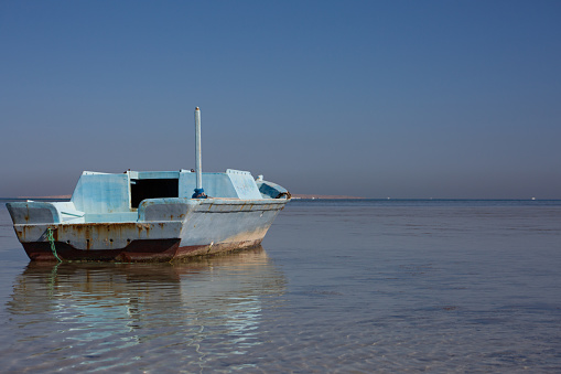 Old abandoned fishing boat washed up in shallow water against the backdrop of a seascape in Egypt