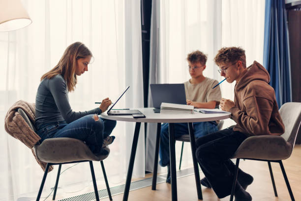 Teenagers using laptops and studying at home