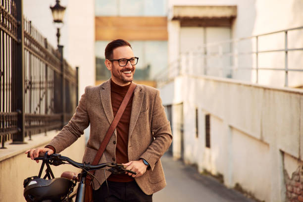 istock A smiling businessman with glasses pushing a bicycle on his way to work. 1992470818