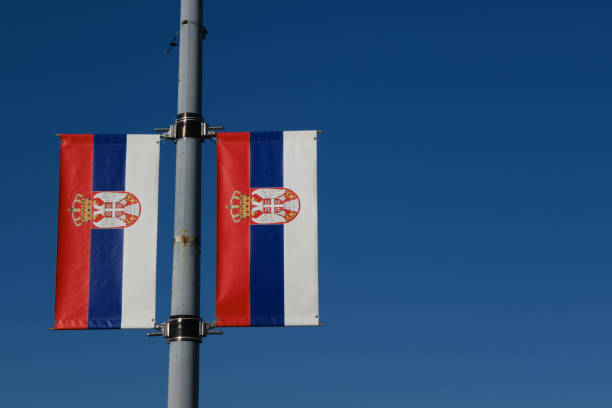 des drapeaux serbes se détachent sur le ciel bleu par une journée ensoleillée dans le centre de belgrade. rouge, bleu, blanc, tricolore avec le symbole des armoiries de la serbie. concept patriotique, arrière-plan avec espace de copie. - commonwealth of nations photos et images de collection