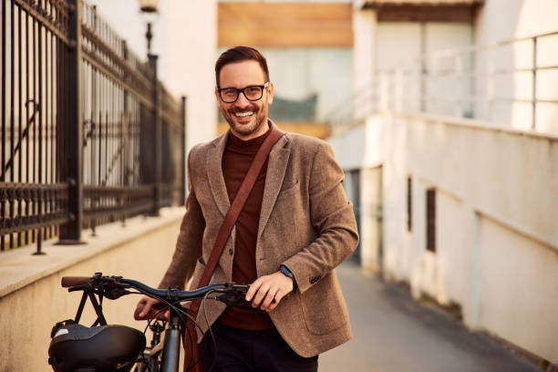 istock Portrait of a happy businessman pushing his bicycle while walking to work. 1992477148