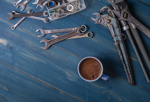 Plumbing Industrial Template. Blue wooden background with different tools. Coffee break. Copy space.