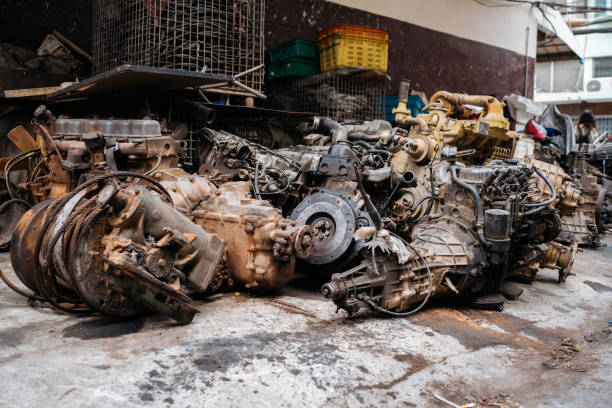 A pile of discarded automotive engines and mechanical parts in an urban scrapyard.