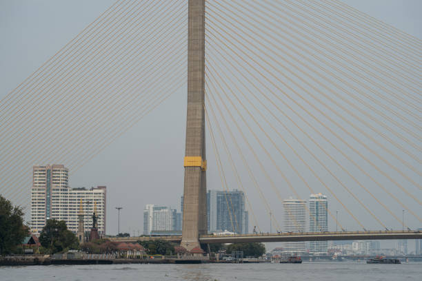 The Rama VIII bridge spans the Chao Phraya River in Bangkok with a cityscape background.