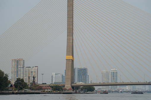 The Rama VIII bridge spans the Chao Phraya River in Bangkok with a cityscape background.