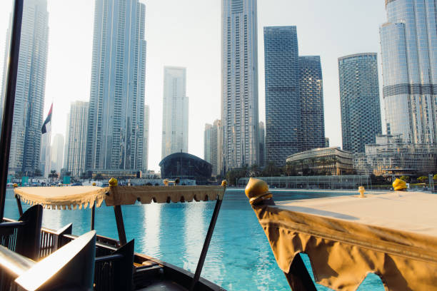 Scenic view of the central district of Dubai city in United Arab Emirates with old boats ob the bay and modern skyscrapers during wonderful sunset time