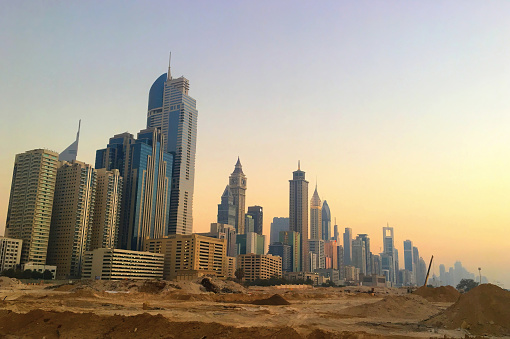 A view of the towers on Sheikh Zayed Road in Dubai at sunset with a construction site in the foreground.