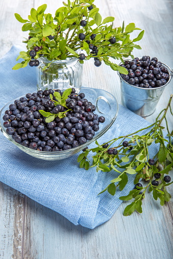 Fresh forest berry, blueberries in a glass plate on a wooden table.
