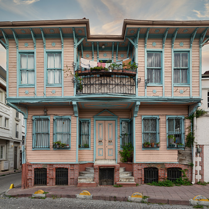 Colorful wooden house with balconies, located in the Fatih district of Istanbul, Turkey. The house is painted in shades of pink and blue, and the balconies are adorned with flowers and plants